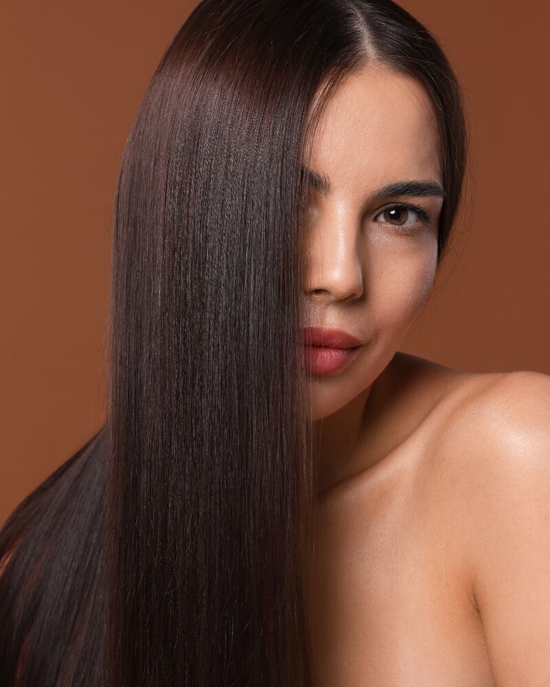 Mujer con una melena morena lisa y brillante que le cubre media cara
