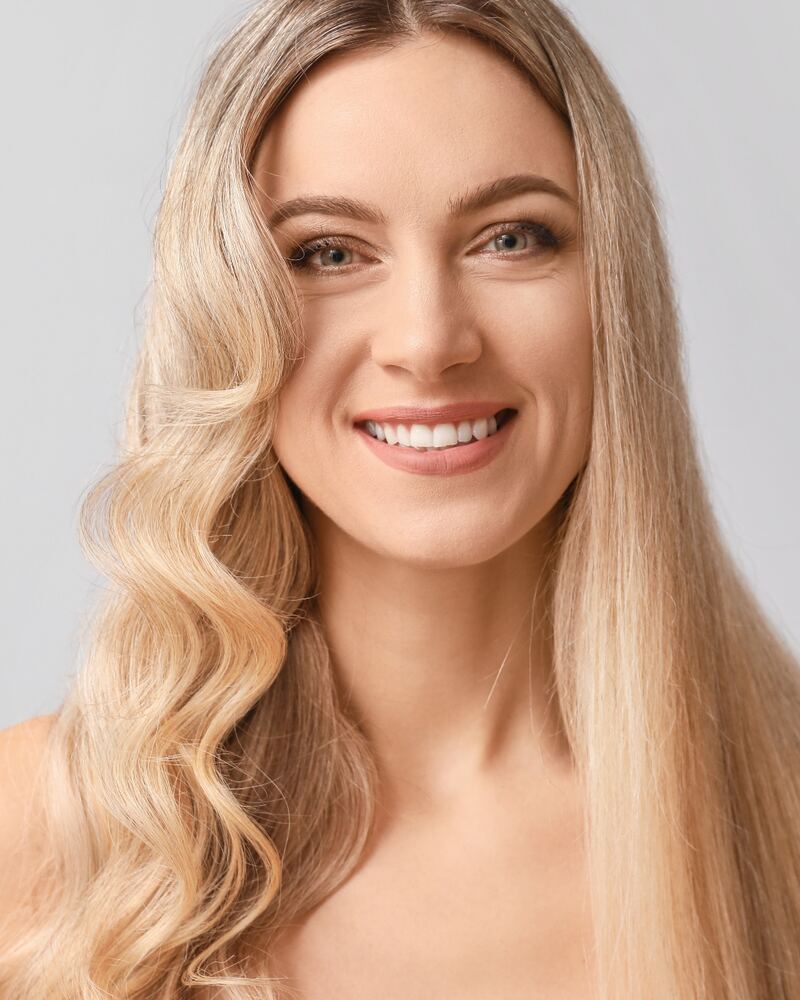 Mujer sonriente con una melena rubia larga y ondulada
