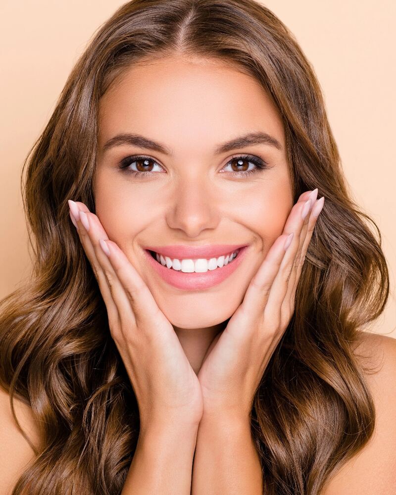 Mujer sonriente con una melena castaña ondulada, suave y brillante