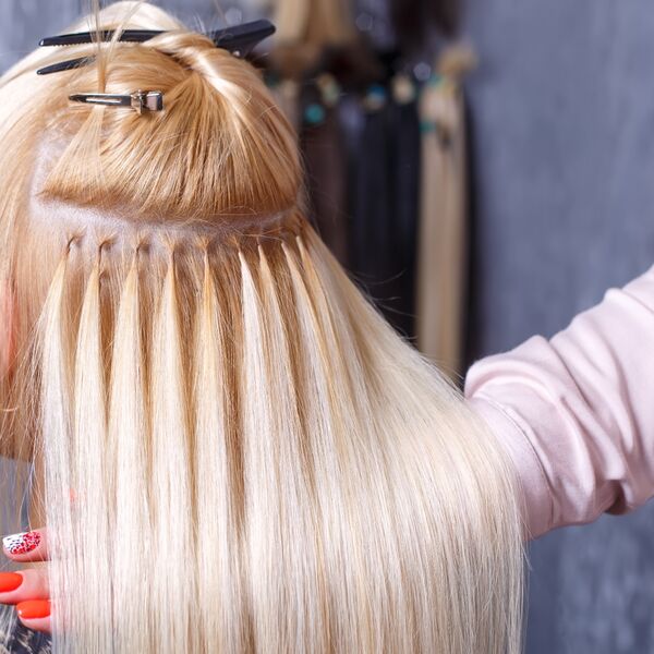 Filas de extensiones adhesivas colocadas en una melena rubia