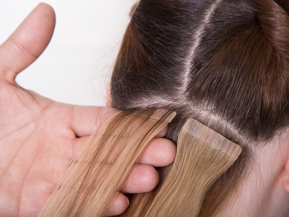 Mano sujetando una extensión adhesiva colocada junto a la raíz